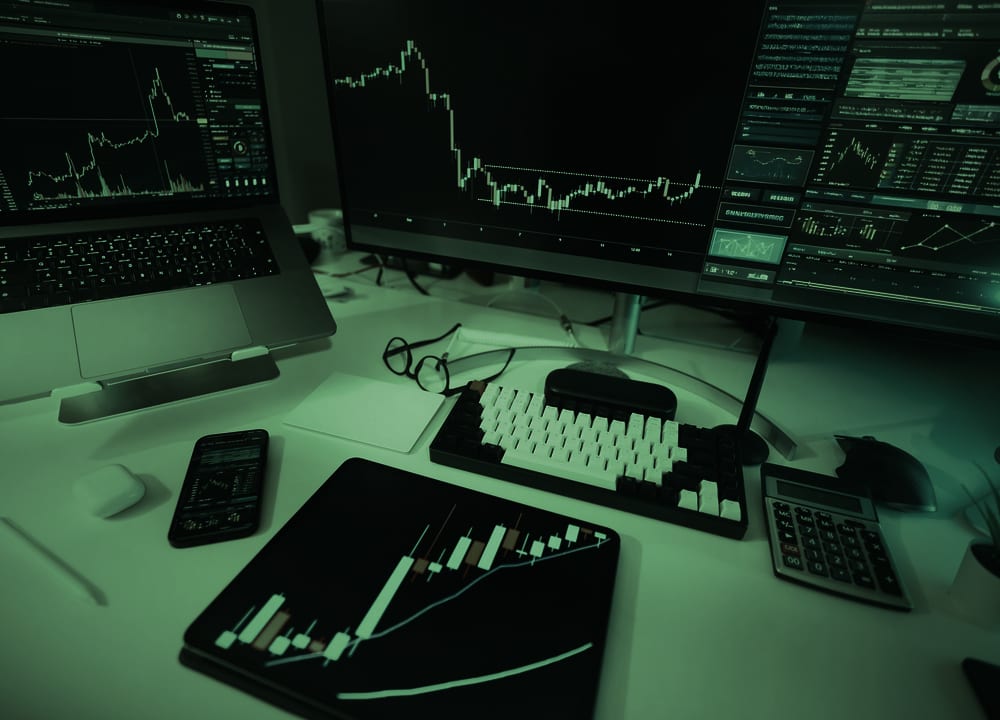 Trading desk with market charts on a monitor, laptop and tablet