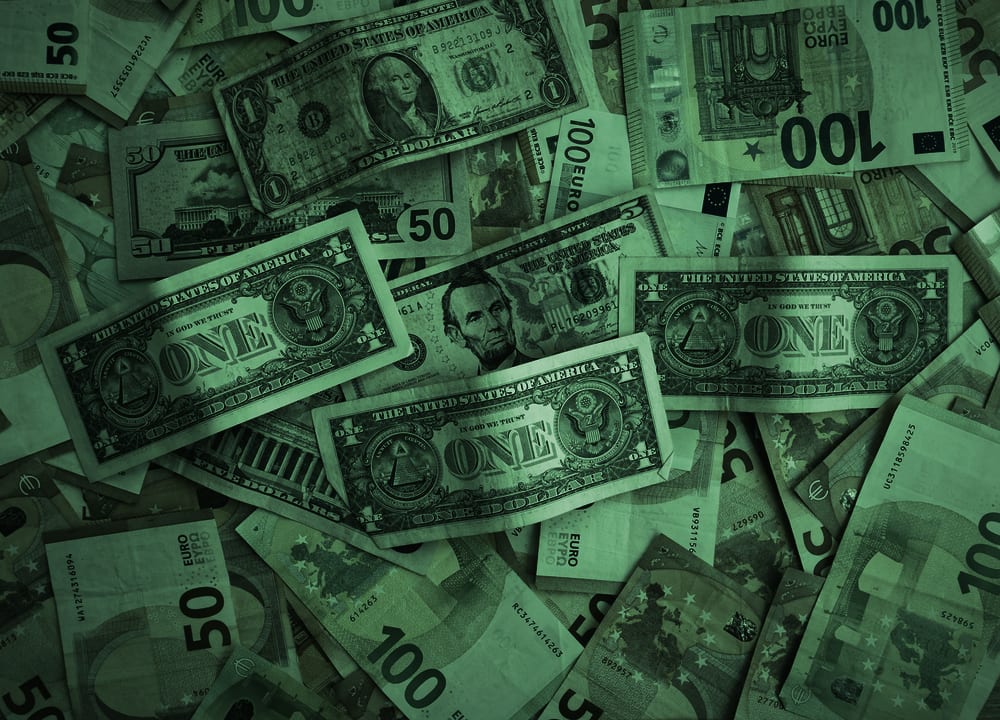 US dollar and euro banknotes spread across a table